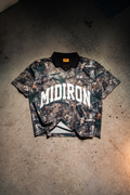 Camouflage polo with 'MIDIRON' branding on a concrete floor